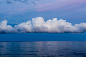 Naklejka premium Stormy day in Sardinia, Italy. A big white cloud over the Mediterranean Sea creates a striking contrast.