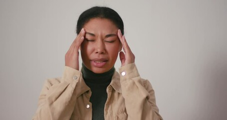 Hispanic woman suffers from headache massaging temples
