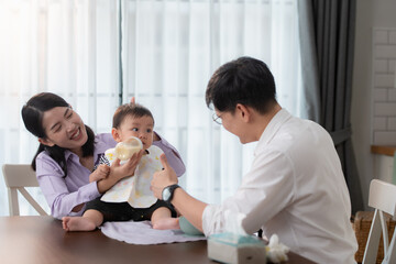 Obraz premium Father and mother feed their son breakfast before going to work in the kitchen of the house