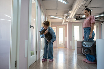 Female owner arrives at animal hotel to drop off cat as staff tours facilities, describes policies....