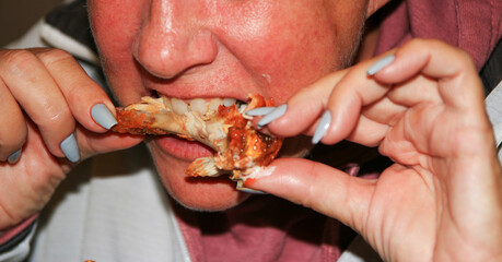 Close up of a women biting into a buffalo chicken wing while eating out