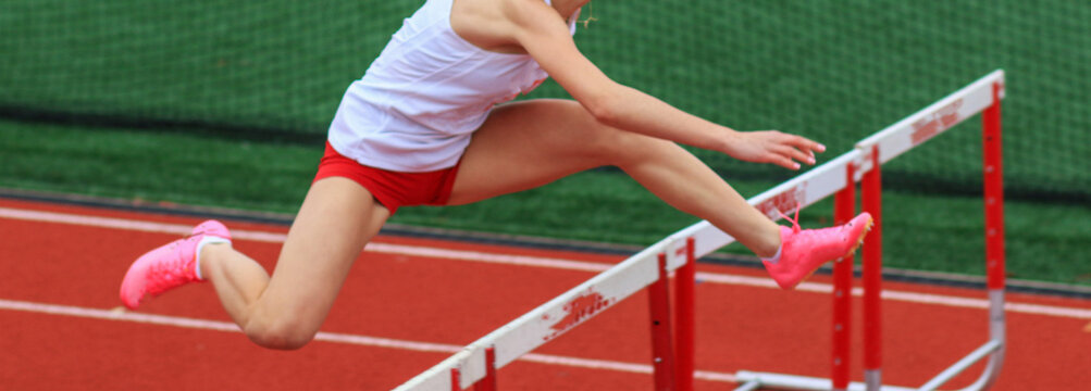 Female Athlete Performs High Jump Over Hurdles During Track Competition on Outdoor Field