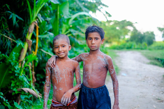 South asian rural kids in outdoor, underprivileged poor children having muddy body, portrait of shirtless young brothers 