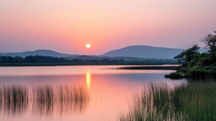 Fototapeta premium Serene sunset over a tranquil lake with distant mountains.