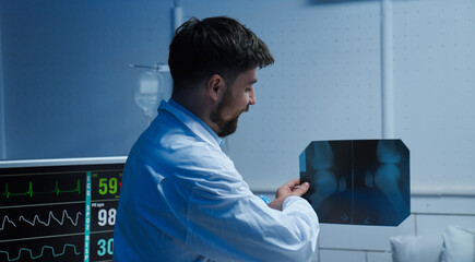 Adult man patient laying in hospital bed, ready to discharge, close up shot of doctor holding and showing x-ray and explaining treatment results.