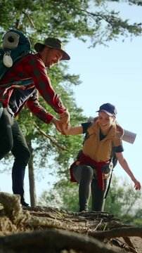 Tourism and travel, portrait of cheerful female hiker smiling to her friend, hike in nature, vertical video. Friendship, support and help, healthy lifestyle and active pastime outdoors, sport and life