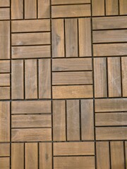 A close-up of interlocking wooden deck tiles, showcasing their geometric pattern and natural...