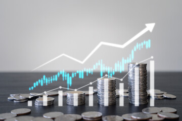 Stacks of coins with candlestick trading graphs showing Profit, financial growth targets, interest increasing, retirement financial, and stock market. Investment and financial concept.