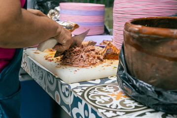Unrecognizable woman serving meat on a plate during a Mexican party.