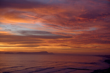 Obraz premium As the sun sets over San Lorenzo Island, the view from Miraflores becomes pure magic .The island silhouettes against a sky ablaze with color, while the ocean whispers of infinite horizons. 
