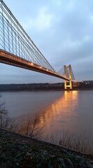 Fototapeta premium A bridge illuminated at dusk, reflecting on calm waters below.