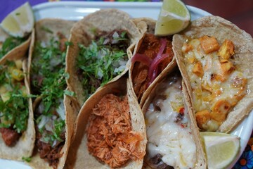 mexican gastronomy. tray with assorted typical tacos garnished with lime and cilantro