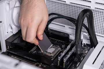spreading thermal paste evenly on cpu surface during pc assembly, hand using a tool for precise...