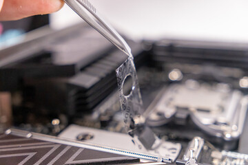 removing protective film, motherboard preparation, m.2 slot, tweezers, hardware installation, computer assembly, precision work, pc upgrade, thermal pad setup, electronics assembly