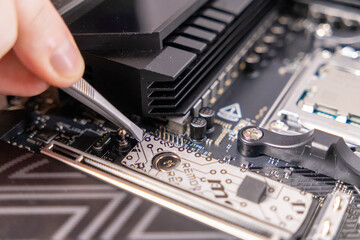 using tweezers on motherboard, precise hardware setup, m.2 slot, thermal pad preparation,...