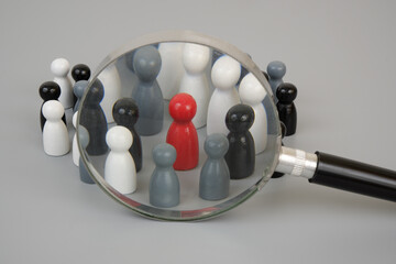 Many wooden people figures  under magnifying glass on gray background. Hire workers concept.