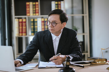 Male lawyer working at desk in office, focusing on gavel and weighing justice.