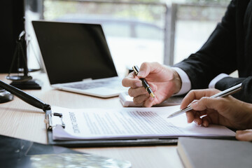 Close up of male lawyer working with contract documents and wooden hammer on table in courtroom....