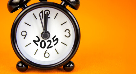 Business concept of 2025 new year symbol. Beautiful orange paper with number 2025. Beautiful orange background, copy space. Black alarm clock. Business 2025 happy new year concept.