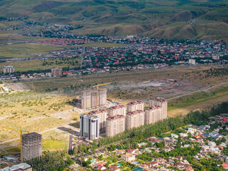 Obraz premium Mountain landscape in summer before the rain. The sun rays break through the clouds. City near the mountains. Top view, drone photo.