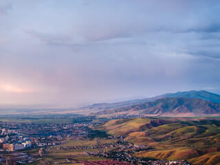 Mountain landscape in summer before the rain at sunset. City near the mountains. Top view, drone...