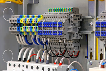 Electrical screw through terminals with connected insulated wires in an electrical switchboard.