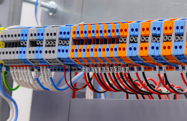 Electrical screw through terminals with connected insulated wires in an electrical switchboard.