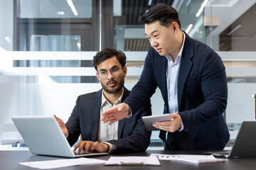 Two business professionals engage in a collaborative discussion in a modern office environment. One...