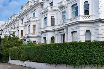 Street with long row of elegant white townhouses in the London Borough of Kensington