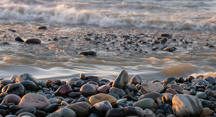 View of empty pebbles beach with splashing sea waves background