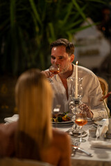 A happy couple enjoying a romantic dinner together, surrounded by a beautiful setting and soft lighting.

