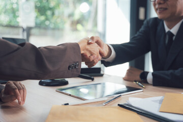 Successful Partnership: Two businessmen shake hands across a table, signifying a successful...