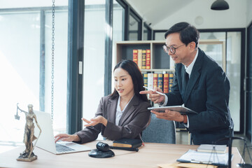Fototapeta premium Lawyers collaborating on a case: A male and female lawyer are working together in an office, discussing a case on a laptop. They are both wearing professional attire, and the office is well-appointed.
