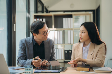 Real Estate Consultation: A professional real estate agent discusses a property plan with a client, demonstrating expertise and trust in a modern office setting. 