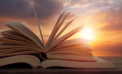 Scriptures on pages open book at bright sunset background