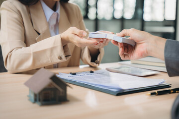 Handing Over The Keys:  A close-up shot of a real estate agent passing house keys to a happy new...
