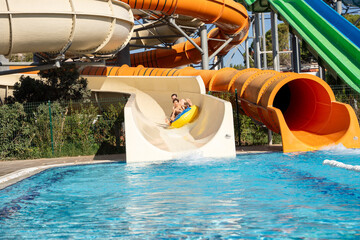 A father and son enjoying their time at an aqua park, playing and having fun on water slides and in the pool.