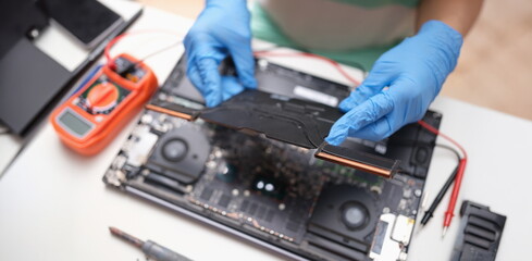 Gloved hands hold a laptop microcircuit, close-up, blurry. Replacement of the motherboard, video card, repair