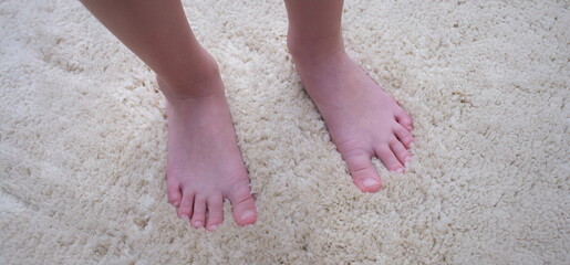 Bare feet of a man on a warm beige carpet, close-up. Soft pile carpet for an apartment. Noise isolation, foot massage
