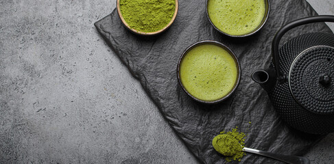 Traditional japanese matcha tea ceremony set on a dark slate plate, including a black iron teapot,...