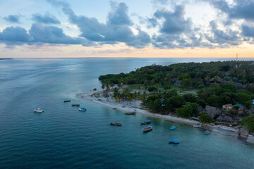 Aerial view of tropical island at sunset, with coconut palm trees and fishing boats near the shore, Utende beach, Mafia Island, Tanzania