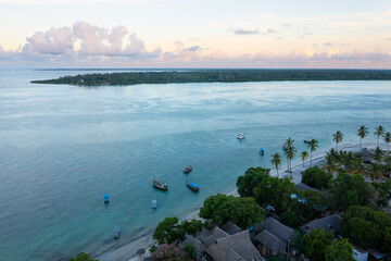 Aerial view of tropical island at sunset, with coconut palm trees and fishing boats near the shore, Utende beach, Mafia Island, Tanzania, Africa, with Chole island on horizon