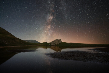 Beautiful night landscape, Bright Milky Way galaxy over the small  lake and mountains. 