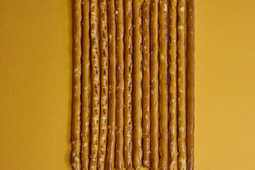 Artfully arranged pretzel sticks are presented beautifully against a vibrant yellow background