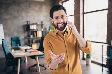 Photo of handsome young guy talk phone dressed yellow shirt formalwear comfortable startup office...