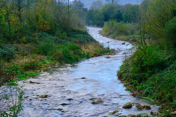 Fototapeta premium Serene flow of the Saja River through the lush Cabuerniga Valley landscape.