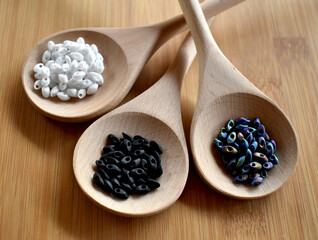 Close-up of beads with various shades of gray on a wooden spoon