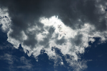 Obraz premium Dramatic cloud formation above a clear blue sky during the afternoon with sunlight breaking through