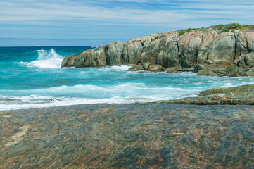 Crystal-clear turquoise waves crash against rugged rocks on the stunning coast of Western Australia. A serene and wild seascape perfect for nature and travel enthusiasts.