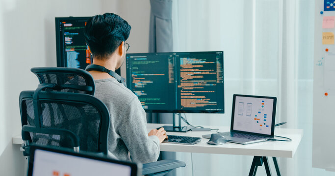 Young adult Asia male freelance eyeglasses typing write prompt AI bot IT app smart program nomad, video game, terminal with coding, user interface, designer, big data center on desktop computer.